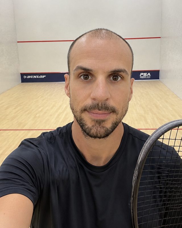 Adrien Cressin sur un court de squash, raquette à la main